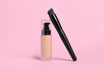 Bottle of skin foundation and brush on pink background. Makeup product