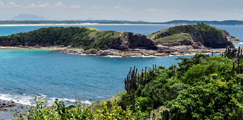 Top view of Praia das Conchas, close to the city of Cabo Frio, blue sky, sea with green waters, with mountains in the background.