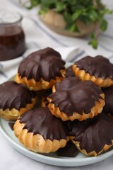 Delicious profiteroles with chocolate spread on table, closeup