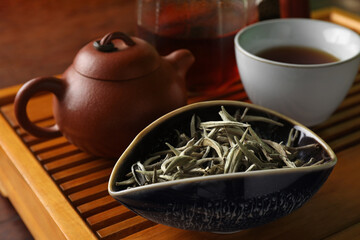 Aromatic Baihao Yinzhen tea and teapot on wooden tray, closeup. Traditional ceremony