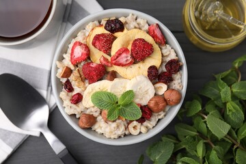 Oatmeal with freeze dried fruits, nuts and mint on grey wooden table, flat lay
