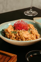 Ceramic plate filled with steaming white rice and shrimp, accompanied by a glass of wine,