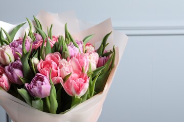 Bouquet of beautiful tulips near grey wall, closeup. Space for text