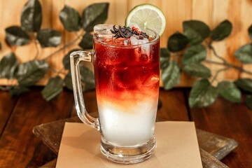A vertical shot of a white and red cocktail with a slice of lemon