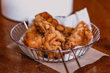 fried food is sitting in a wire basket on a napkin