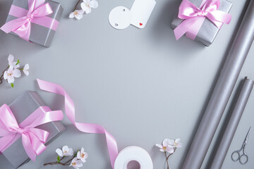 Frame of wrapping materials on light gray background. Gift box, wrapping paper, gift tags, ribbon, scissors. Copyspace.