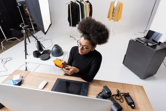 high angle view of african american retoucher choosing colors near computer and graphic tablet in photo studio.
