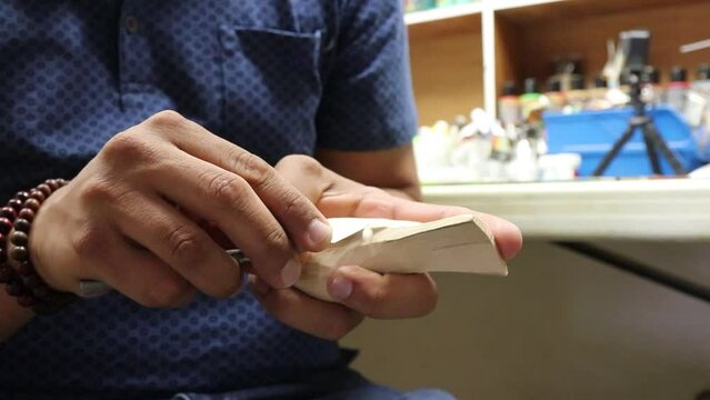 Closeup of a talented artisan man carving a white wooden bird craft