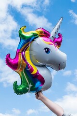 a person holding a unicorn foil balloon in the air while the woman's arms