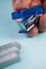 a small blue stapler being held in front of a blade