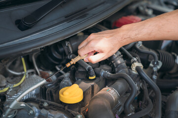 Young man checking and maintenance oil quality the engine on his car. Car repair and maintenanc concept.