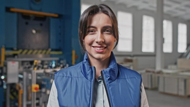 Close-up portrait of young beautiful nice alluring magnificent Caucasian female indoors at industrial workplace. Serious employee start smiling chuckling showing positive emotions.