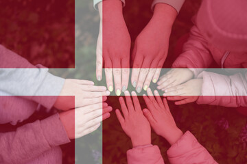 Hands of kids on background of Denmark flag. Danish patriotism and unity concept.