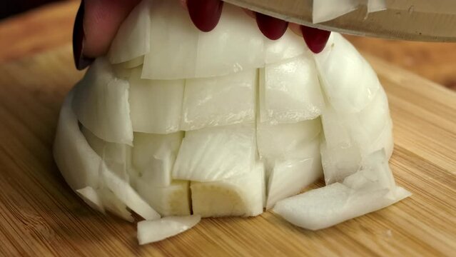 Knife chops white onion into pieces