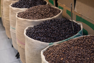 Freshly roasted coffee beans with a metal scoop, in jute sacks. Close-up with an open coffee bag....