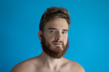 portrait of a young handsome man without clothes on a blue background