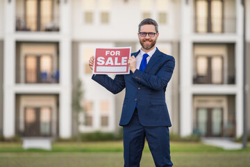 Successful real estate agent in suit with sign for sale. Real estate broker front of new house....