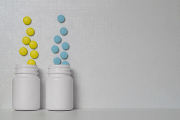 Yellow and blue pills fly out of two white plastic jars
