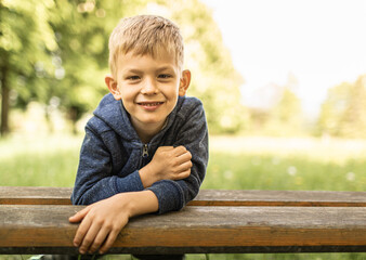 Portrait of cute smiling little blond boy outdoors with natural sunlight 
