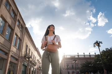 Adult tourist woman walking through the city at sunset with the sun behind. solo traveler concept