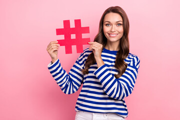 Photo of young curls girl wear striped pullover hold paper hashtag pin social media blogger popular trend isolated on pik color background