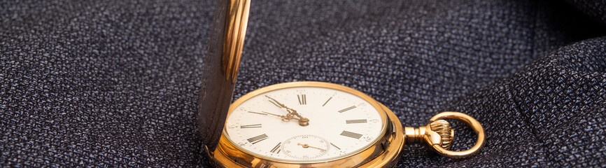 Golden pocket watch on the background of a man's suit.Retro style and vintage fashion.