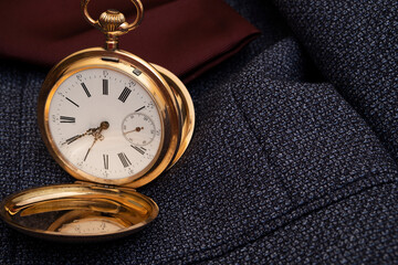 Golden pocket watch on the background of a man's suit.Retro style and vintage fashion.