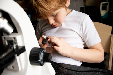 child with microscope. Schoolboy researching glasses with laboratory materials under microscope. Science education