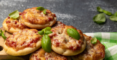 pizzetta - Italian mini pizza with tomato sauce, mozzarella cheese and salami. selective focus. Homemade Mini Pizza with basil leaves on a wooden board