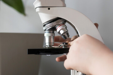 Close up of child hands installing glass with laboratory materials in microscope for research, science lab kids concept