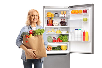 Woman with a grocery bag posing in front of an open fridge