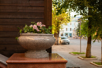 Stone flowerpot with flowers on a city street.