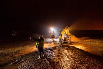 Ust-Luga, Leningrad oblast, Russia - November 16, 2021: Road construction site at night. Worker...