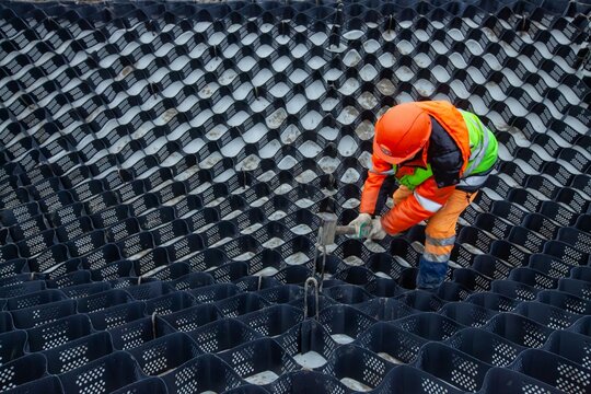 Ust-Luga, Leningrad oblast, Russia - November 16, 2021: Worker installing HDPE Geocell Ground Grid Paver. Plastic Geocell For Construction