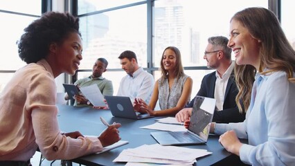 Multi-cultural business team meeting around office boardroom table with laptops discussing documents - shot in slow motion - Powered by Adobe