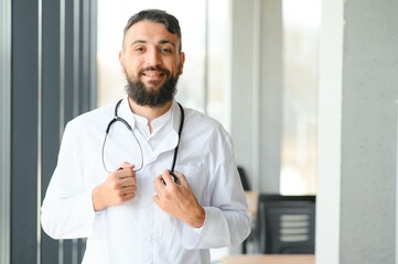 Handsome hispanic doctor man wearing stethoscope at the clinic with a happy and cool smile on face....