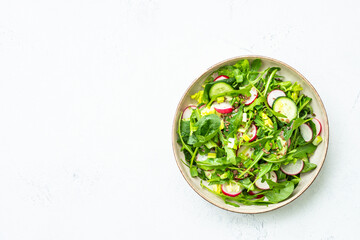 Green salad with spinach, arugula and radish with olive oil. Top view on white.