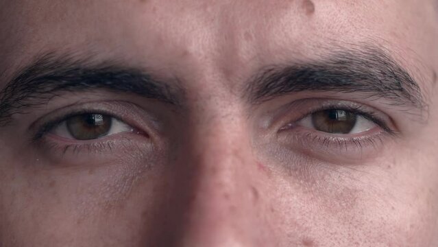Extreme close up opening beautiful brown eyes of young man slow motion. Facial expressions, concept of emotions