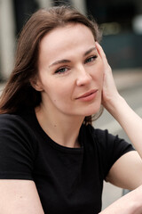 Relaxed young woman is looking at camera in the street.