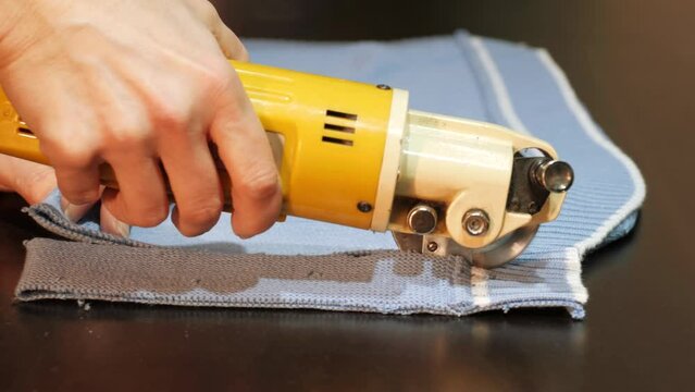 Electric cutter Fabric Machine. Cutting a knitted fabric with in an workshop. Drapery Shop. Sewing, Tailoring and Clothes Making. Textile in textile factory.