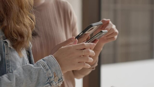 Young adult asian women traveller talking together and using smartphone for checking boarding time at airport. Lifestyle and travel concept.