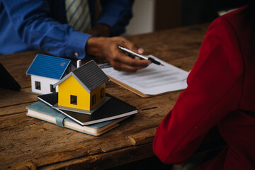 Real estate broker agent presenting and consult to customer to decision making sign insurance form agreement, buy and sell home model, concerning mortgage loan offer for and house insurance