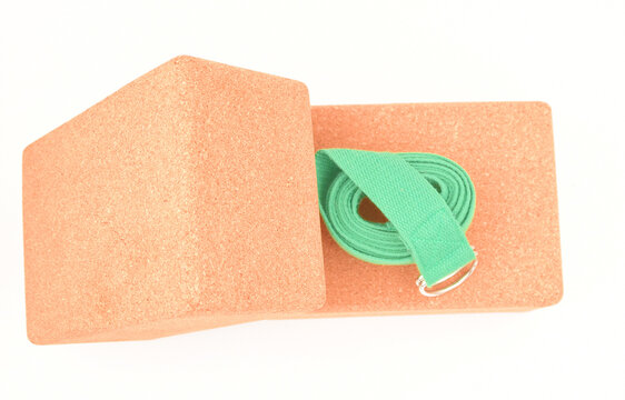 Two cork yoga blocks and green strap isolated on a white background