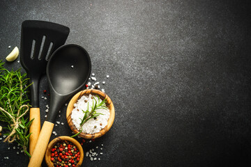 Food background on black. Herbs, spices and utensil for healthy cooking. Top view with copy space.
