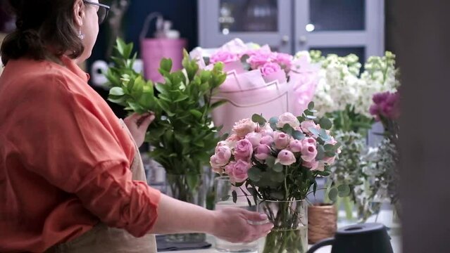 With deft hands and a keen eye for detail, the professional female florist arranges a stunning bouquet of mixed flowers