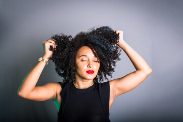 Portrait of beautiful young brunette woman messing with her hair. Dressed in black.