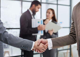 close-up of a handshake of business partners against the background of colleagues