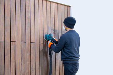 Professional renovation of hardwood cladding, man sanding, removing oxidation and dirt cleaning...