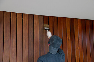 Woodworker is treating hardwood siding with oil protection