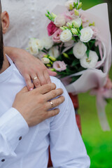 Obraz na płótnie Canvas Wedding gold rings on the hands of the newlyweds, a bouquet of flowers in the background. Gold rings on the hand of a man and a woman